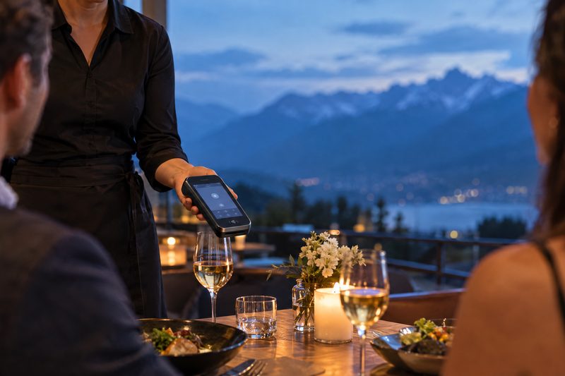 Server presenting a handheld payment device at a dinner table